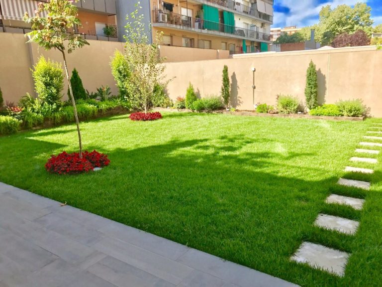 Jardín residencial con césped natural y sendero de piedra de SUMCO, ideal para espacios verdes modernos